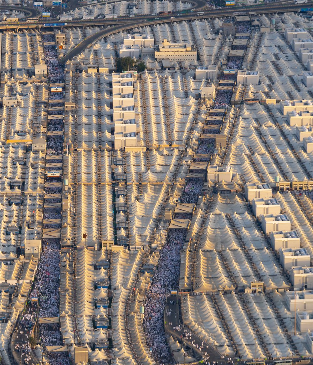 Pilgrims moving along two pedestrian corridors between rows of tents in Mina.